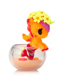 The Tokidoki Neon Reef Mermicorno Blind Box by tokidoki (IT) features a small orange and pink unicorn figurine with a flower crown in a clear sand-filled container, designed to glow under blacklight.