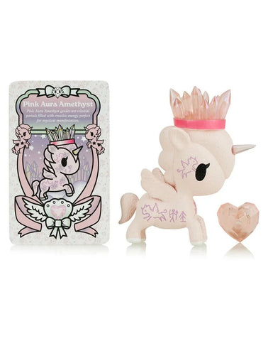 The tokidoki Precious Unicorno - Pink Aura Amethyst (Special Edition) features a pink unicorn figurine with a crystal crown, a heart-shaped gem, and a "Pink Aura Amethyst" card with matching unicorn art, symbolizing healing.