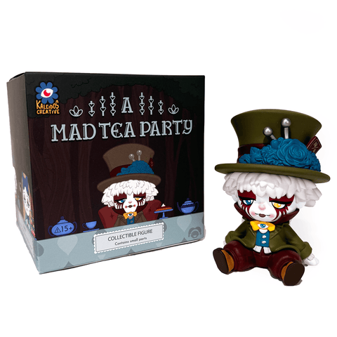 A whimsical collectible with white hair, a green jacket, and a large green hat sits beside Kaleidos Creative's "A Mad Tea Party Blind Box," evoking circus clown charm in its playful design.
