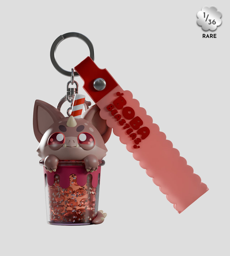 The Boba Beasteas Blind Box by Kaleidos Creative features a cryptid cuties cat keychain in a boba tea cup with a straw, red glitter inside, and a red scalloped