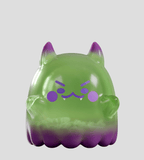 A translucent green and purple cat-like figurine with fangs and pointy ears, the Cute as Heck! Blind Box by Kaleidos Creative is perfect for collectors and stands out boldly against a gray background.