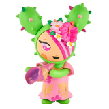 The tokidoki Hawaiian Ohana Blind Box figure features green cactus-like ears, a pink dress with leaf patterns, a pink flower crown, pink hair streaks, and holds a purple object.