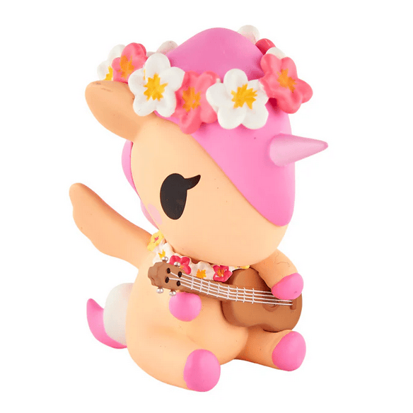A pastel unicorn with a pink mane, flower crown, and brown ukulele sits upright facing left—part of the tokidoki Hawaiian Ohana Blind Box series.
