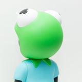 A limited edition Phibby — OG (Green) vinyl figurine by Hebru Brand (US) features a green, frog-like character in a blue shirt with its back turned, set against a plain white background. The design is inspired by the unique style of Hebru Brantley.