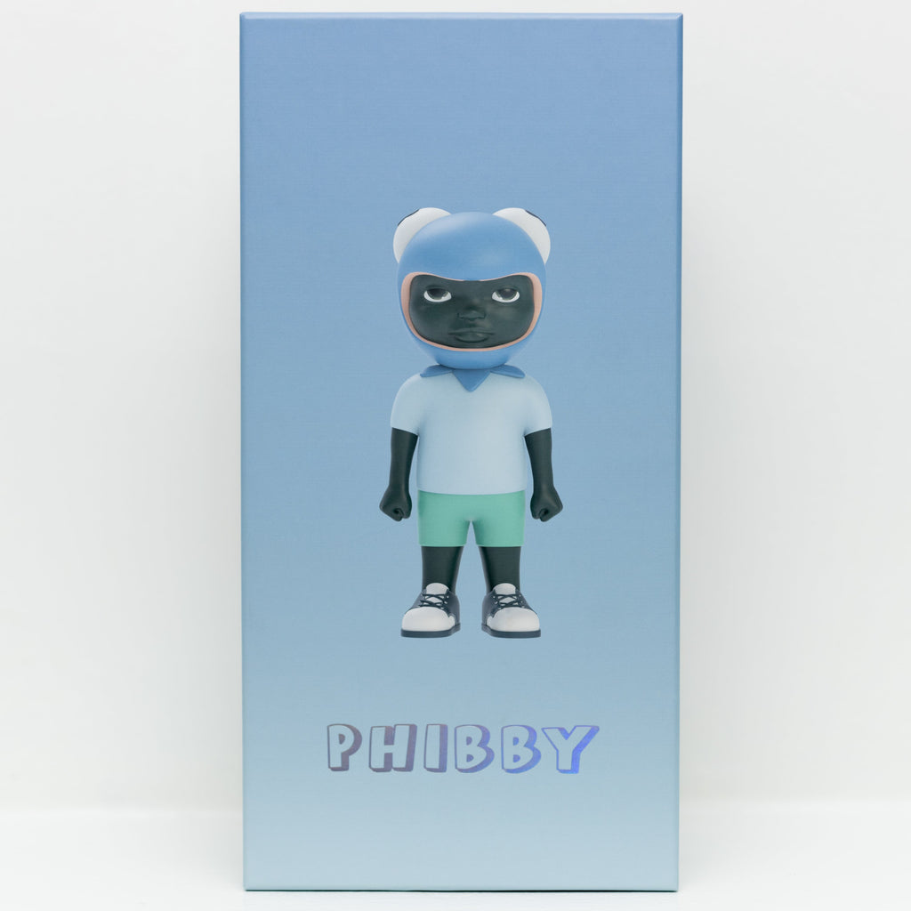 A rectangular box adorned with an illustration of a toy figure by Hebru Brand (US), featuring the figure in a blue helmet, light blue shirt, and green shorts. The word