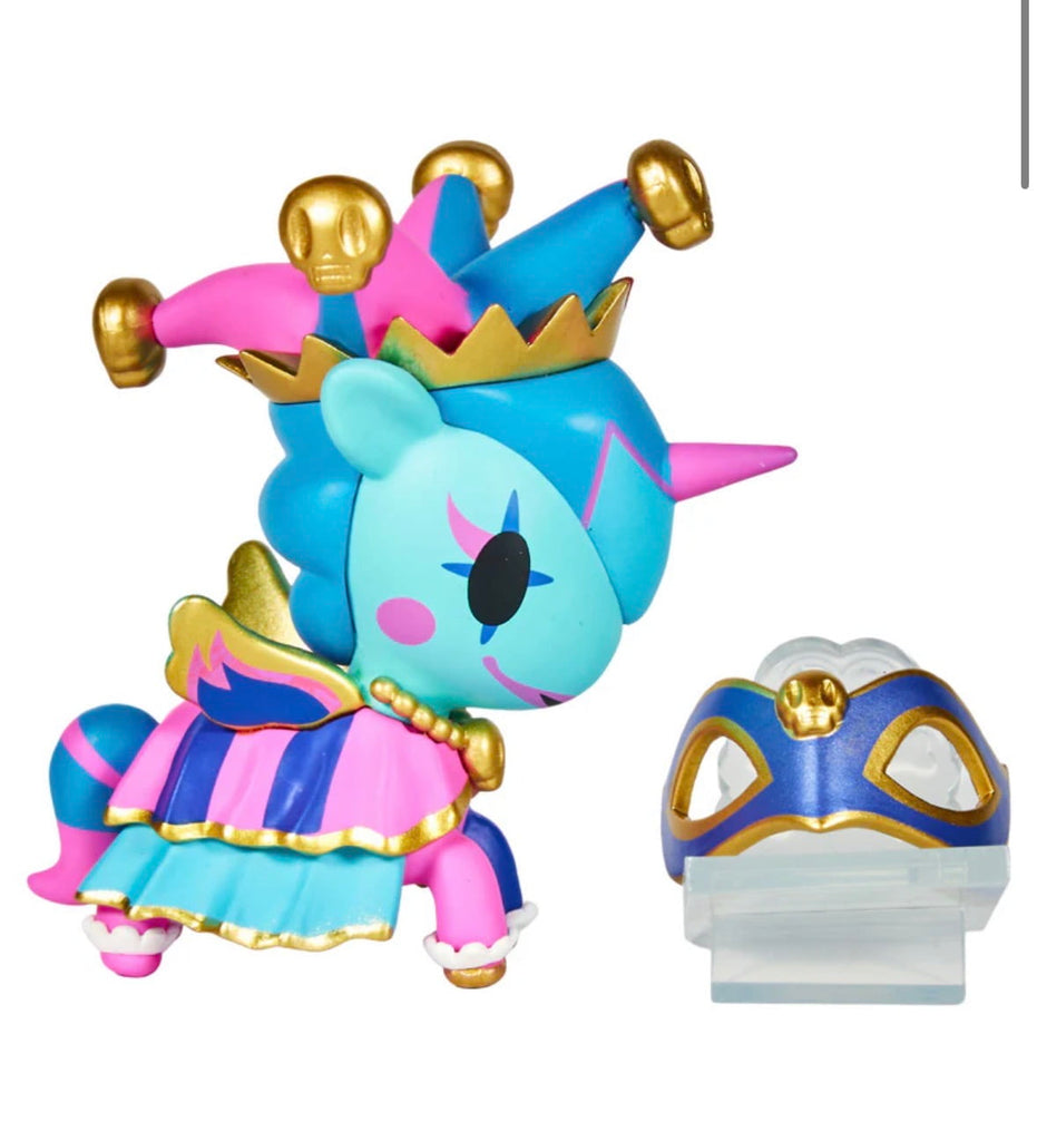 A Tokidoki Unicorno After Dark Masquerade Blind Box collectible, dressed in a jester outfit with gold accents, stands beside a blue and gold mask on a white background.