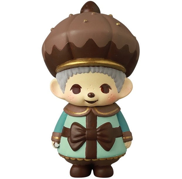 VAG 45 — Monchhichi Happy Gift Box by Medicom (JP) features a Japanese vinyl figure with a large chocolate-shaped hat, light blue outfit, and big brown bow—perfect for fans of Vinyl Artist Gacha and gachapon collectors.