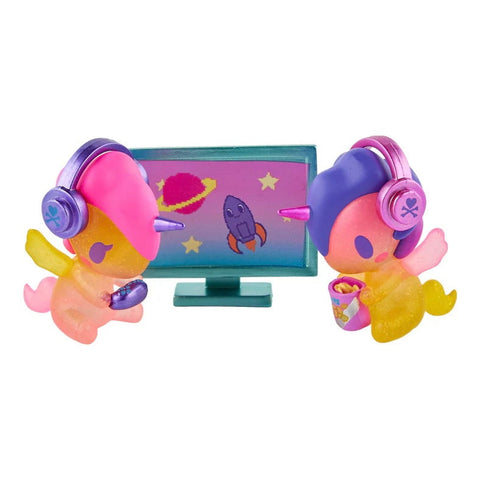 Two vibrant Tokidoki Twinsies Unicorno - Gamer & Streamer (Special Edition) figures with headphones sit before a cosmic screen—one gaming, one snacking—making them the perfect Tokidoki collectables for fans and streamers alike!.