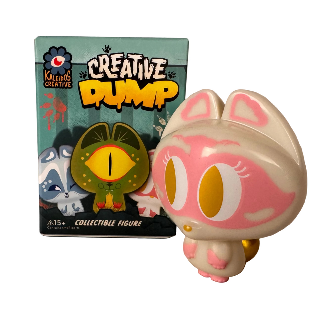 A vinyl cat collectible stands next to its colorful Creative Dump Blind Box, featuring illustrated characters and Kaleidos Creative branding.