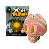 A vinyl cat collectible stands next to its colorful Creative Dump Blind Box, featuring illustrated characters and Kaleidos Creative branding.