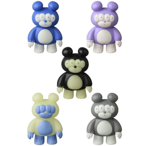 Five VAG 46 — Matthew Japanese vinyl toys by Medicom, each with three eyes and round bodies in blue, purple, black, yellow, and gray, are arranged V-shaped on a white background like playful gachapon collectibles.