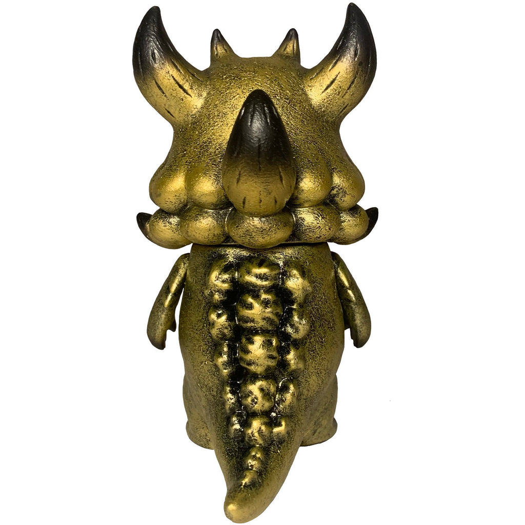 The Little Hut (HK) Rangeas Jr. - Gold Patina is a gold and black horned monster figure with a textured tail and small arms, shown standing upright from behind—an eye-catching collectible toy.