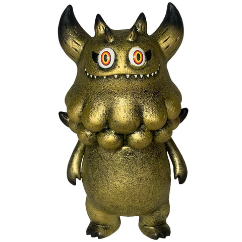 Rangeas Jr. - Gold Patina by The Little Hut (HK) is a gold textured monster figure with horns, sharp teeth, red and yellow eyes, and round neck bumps—an eye-catching collectible toy displayed upright on a white background.