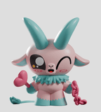 The Kid Krampus Blind Box by Kaleidos Creative features a pastel cartoon goat with teal horns, holding a pink heart-shaped wand and chain—an ideal holiday collectible displayed on a light background.