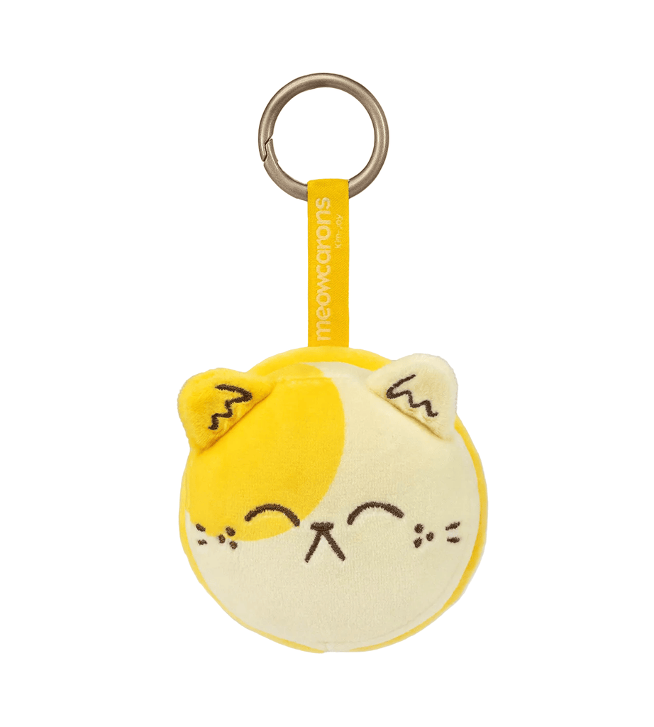 The Meowcaron Plush Bag Charm by Kaleidos Creative features a yellow and cream cat face with embroidered details on a metal keyring, labeled