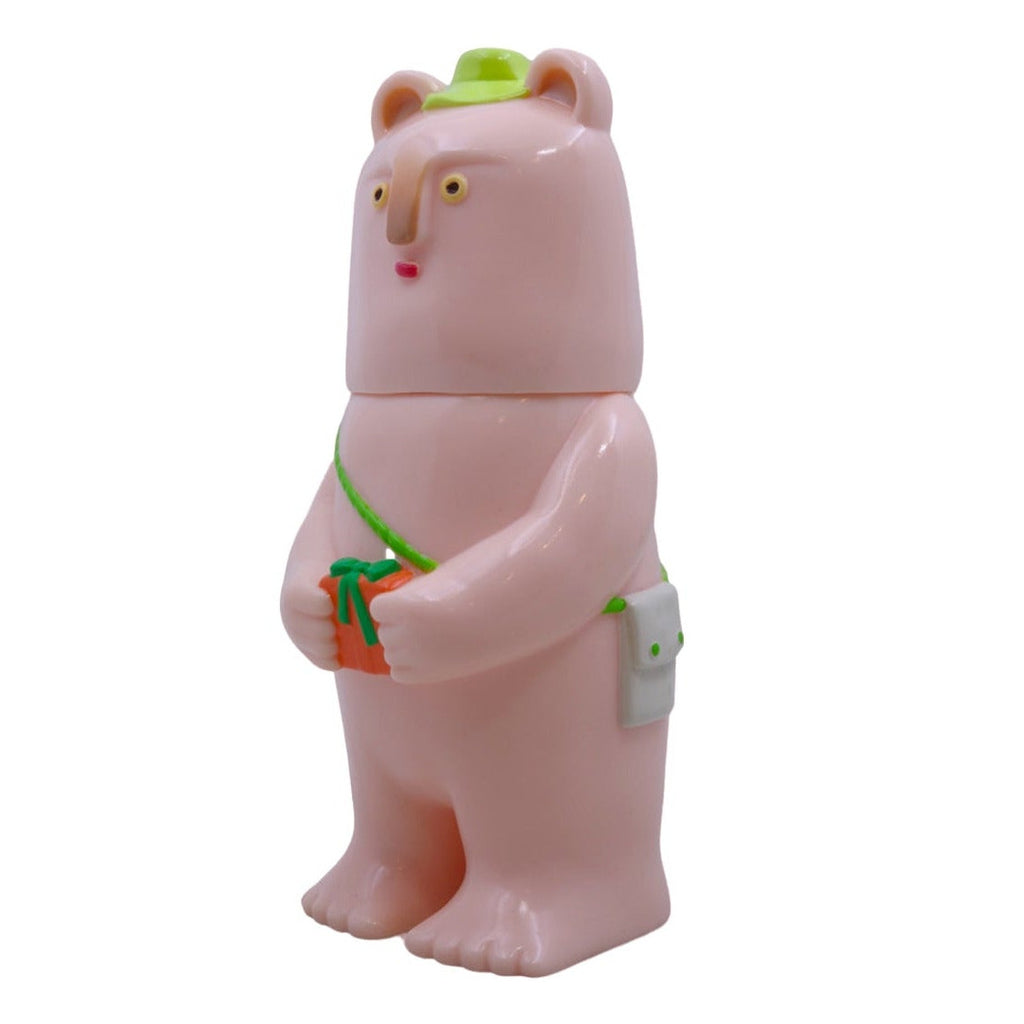 Kurichan - #5 by Paradise Toy is a pink bear figurine with a green hat and bag, holding an orange and green gift, standing upright against a white background and radiating endless cuteness.