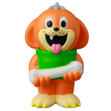 The VAG 43 — Uluru by Medicom (JP) is a cartoonish orange dog figurine with a big smile, holding a green pillow and a white bone, inspired by Japanese vinyl toy style, isolated on a white background.