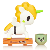 A Tokidoki Sushi Unicorno Blind Box on a wooden base next to a cup.