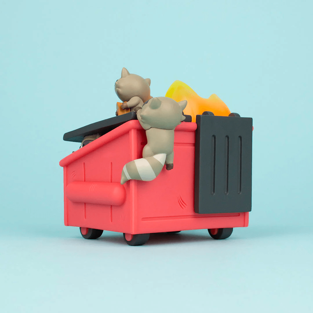 Toy cats playing in a miniature Dumpster Fire - Trash Panda Vinyl Figure against a blue background by 100% Soft.