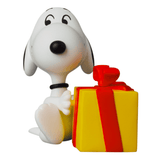 A Gift Snoopy figurine from Medicom (JP) sitting next to a yellow gift box with a red ribbon, perfect for any occasion.