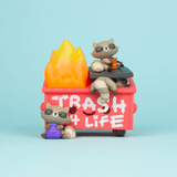 A 100% Soft vinyl toy set featuring raccoons interacting with a Dumpster Fire - Trash Panda Vinyl Figure labeled 