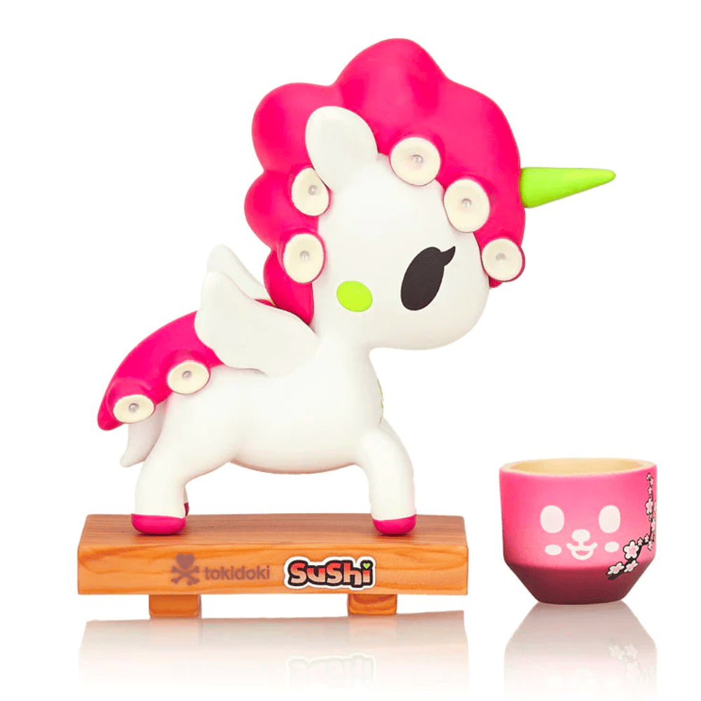 A pink Tokidoki Sushi Unicorno Blind Box toy is next to a cup.