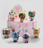 Seven colorful cat figurines with large eyes are displayed in front of a Kaleidos Creative Widdle Baby Blind Box, which features branding and illustrations and offers the chance to discover a rare hidden figure inside.