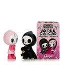 Two cartoon figurines, one in a pink outfit and the other in a black outfit, stand next to a pink box labeled