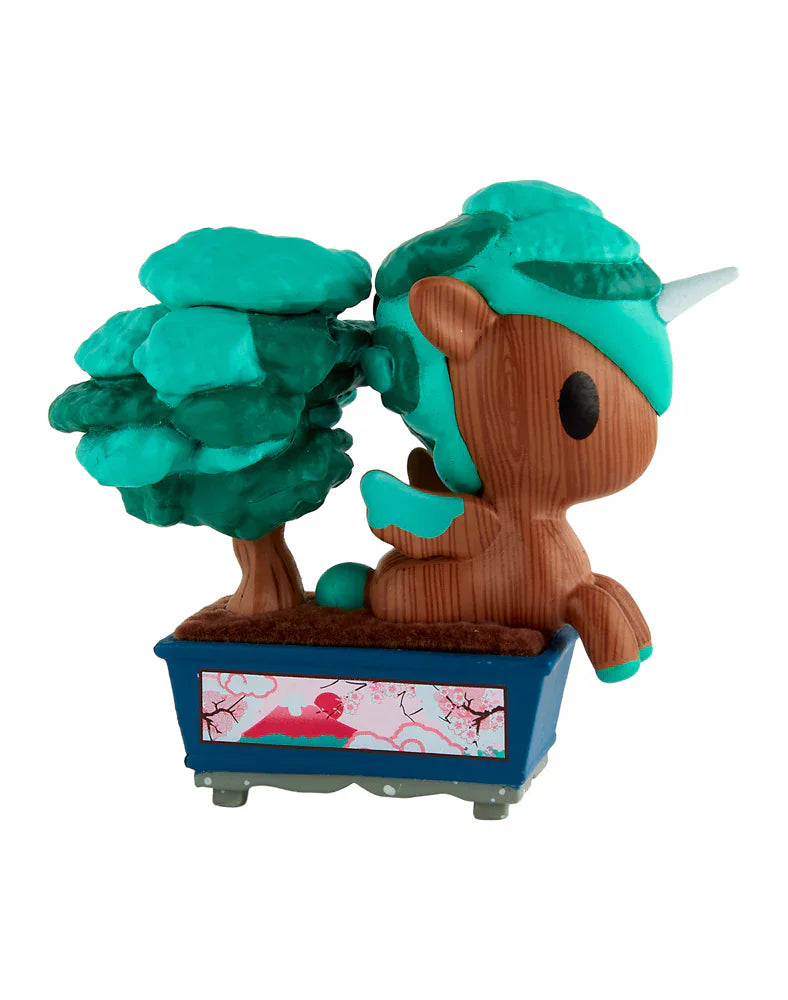 The tokidoki Botanical Bonsai Unicorno Blind Box features a wood-textured Unicorno beside a green tree in a blue cherry blossom planter—a charming addition to any tokidoki mini garden collection.