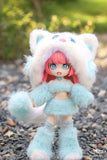 A BIJIDI Cat Island — Black Cat Or Candy Cat? Blind Box ball-jointed doll with pink hair wears a fluffy blue and white cat-themed outfit with hood and ears, standing on gravel with greenery in the background.
