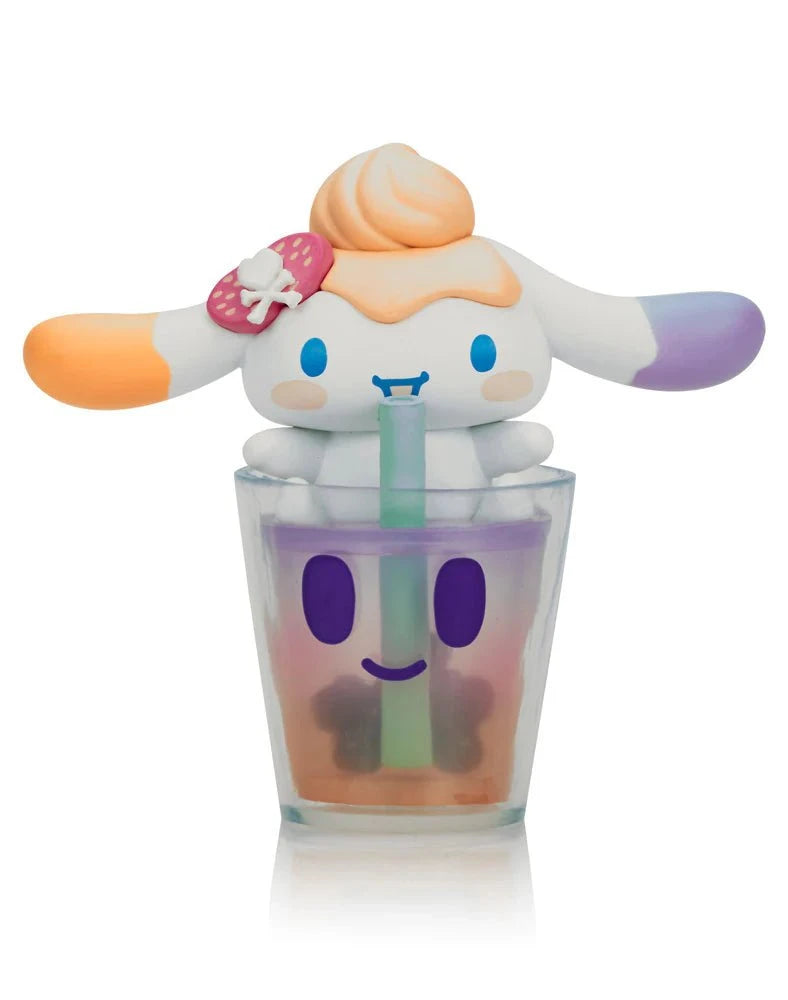 A Tokidoki x Cinnamoroll Sweet Treats Blind Box figure with long ears, orange and purple accents, and a swirl on its head sits atop a smiling cup with green straw—a charming collectible from Tokidoki.