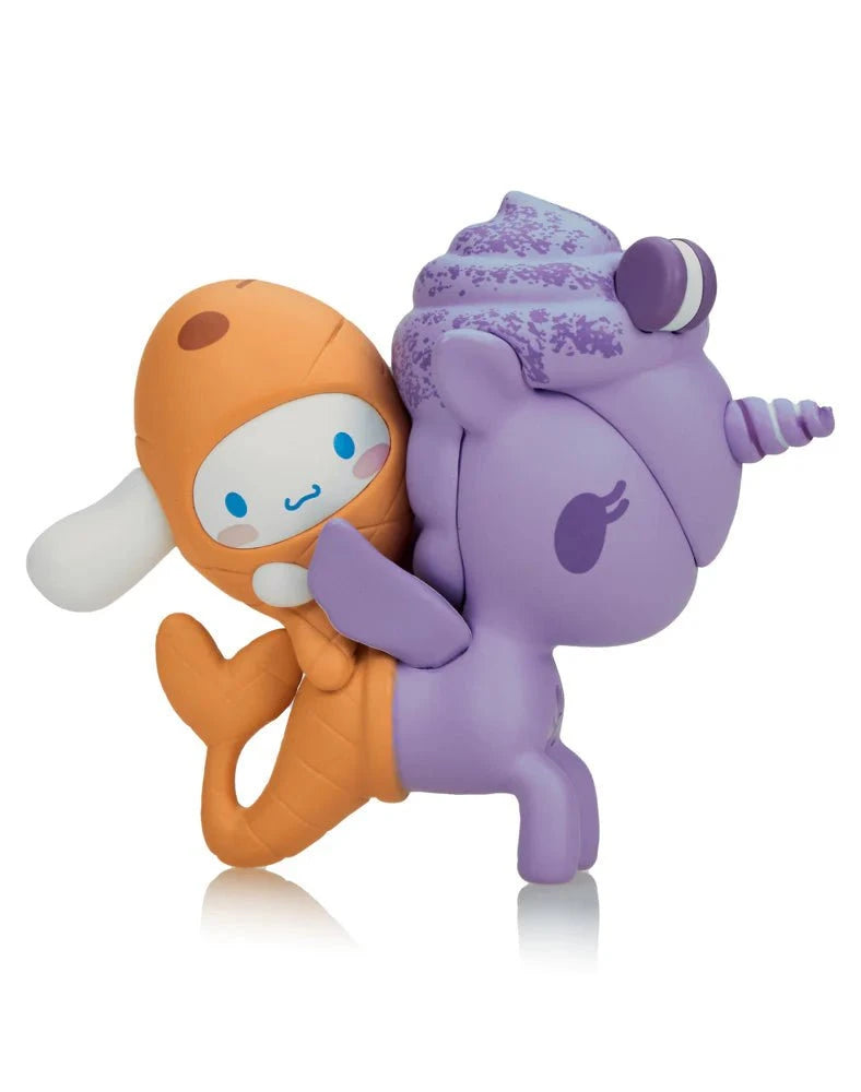 A charming figure from the Tokidoki x Cinnamoroll Sweet Treats Blind Box by Tokidoki depicts a small character in an orange outfit riding a purple unicorn with a swirled mane and horn.