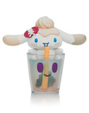 The Tokidoki x Cinnamoroll Sweet Treats Blind Box by Tokidoki features an adorable Cinnamoroll with a swirl head and strawberry bow sitting in a smiling bubble tea cup, holding a yellow straw.