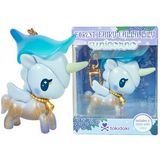 A small unicorn keychain with a blue hat, gold chain, and glitter is displayed next to its box labeled “Forest Fairy Calla Lily Special Edition Unicorno Keychain” by tokidoki. Part of the Forest Fairies Collection, the box features blue and purple floral designs inspired by fairy-themed motifs found throughout the Unicornos lineup.