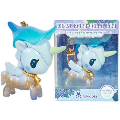 A small unicorn keychain with a blue hat, gold chain, and glitter is displayed next to its box labeled “Forest Fairy Calla Lily Special Edition Unicorno Keychain” by tokidoki. Part of the Forest Fairies Collection, the box features blue and purple floral designs inspired by fairy-themed motifs found throughout the Unicornos lineup.
