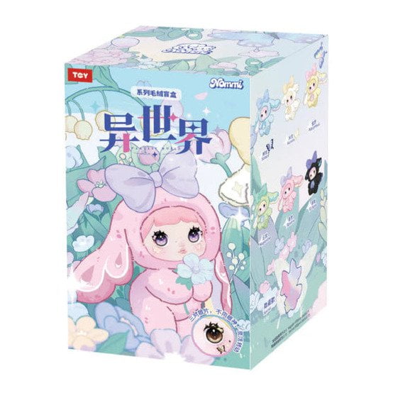 A Nommi Fantasy World Plush blind box featuring a cartoon illustration of a character with large eyes wearing a pink bunny-ear hood, with smaller plush designs displayed on the side.