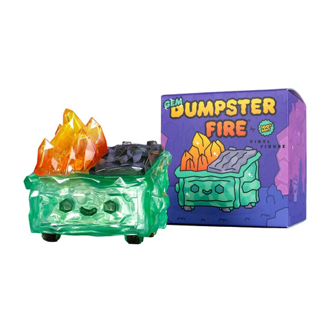 The 100% Soft Gem Dumpster Fire Vinyl Figure features translucent green vinyl, orange crystal-like flames, and a smiling face beside its colorful "Gem Dumpster Fire" packaging.