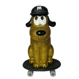 The How 2 Work One Chu Sk8- Gold features a gold glitter cartoon dog wearing a black cap, confidently sitting on a skateboard and sparkling with style.