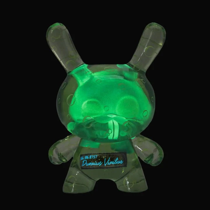 The Kidrobot Infected Specimen Dunny 8” GID Art Figure (LE 600) glows green with bubble details against a black background, featuring handwritten text on its torso to highlight its limited edition status.