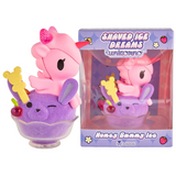 A special edition tokidoki Shaved Ice Dreams Unicorno Honey Bunny Ice figure features a pink unicorno nestled in a purple bunny-shaped shaved ice dessert with a cherry on top, accompanied by its matching box labeled “Shaved Ice Dreams Unicorno Honey Bunny Ice.” This charming collectible adds a magical tokidoki touch to any sweet collection.