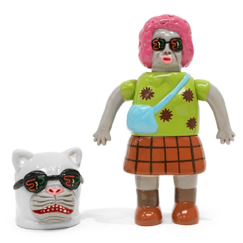 A toy figure with a pink wig, green shirt, and plaid skirt stands next to a cat head with sunglasses features the product