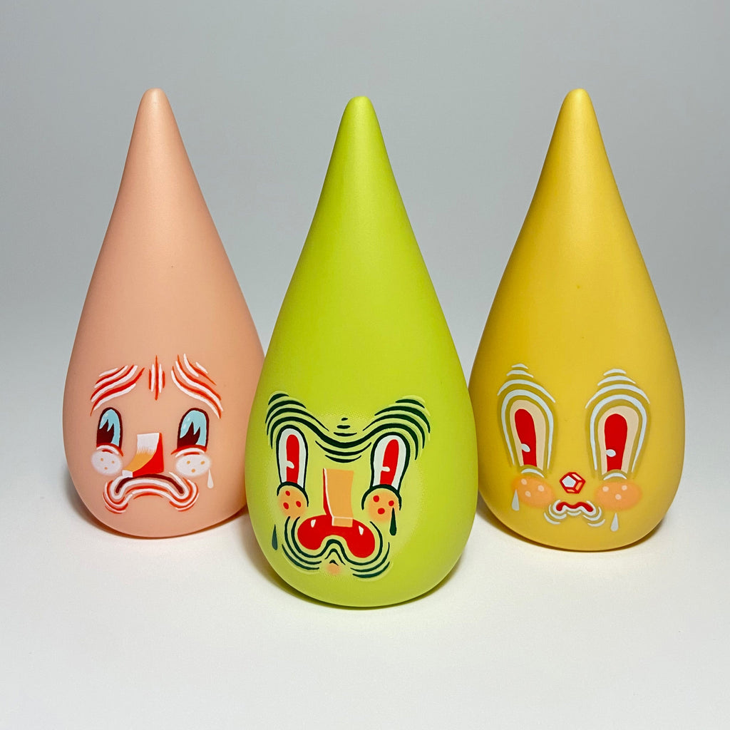 Three colorful, teardrop-shaped figurines, known as Mini Driplets — Primo & Plebe Blind Box by Squibbles Ink + Rotofugi (US), with painted faces displaying various expressions are lined up against a plain background.