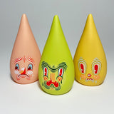 Three colorful, teardrop-shaped figurines, known as Mini Driplets — Primo & Plebe Blind Box by Squibbles Ink + Rotofugi (US), with painted faces displaying various expressions are lined up against a plain background.