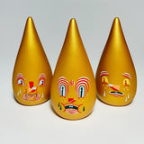 Three golden teardrop-shaped figures, known as Mini Driplets — Primo & Plebe Blind Box by Squibbles Ink + Rotofugi (US), with expressive, painted faces are lined up on a white background.