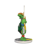 A side view shows the Kidrobot Teenage Mutant Ninja Turtles TMNT GURU Resin Figure by CHOGRIN, featuring a colorful TMNT character with a sword, standing on a round patterned base.