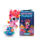 A pink unicorn figurine with a coral-style mane and sunglasses sits in a glass bowl next to the tokidoki (IT) Neon Reef Mermicorno Blind Box, featuring an underwater reef design. Some figurine details glow under blacklight for added magic.