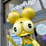A vinyl version of Dalek Space Monkey — Gold Rotofugi Exclusive holding a sword in front of a store by UVD Toys (US).