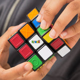 A person’s hands hold and turn the Spinmaster Rubik's CNIB SmartLife Sensory Cube, featuring textured, colorful tiles for accessibility—making it ideal for visually impaired users.