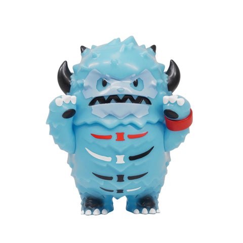 Lucas — Aurora Adventure by The Little Hut: a blue, spiky cartoon monster figurine with black horns, red wristband, and white, red, and black body markings—standing upright with arms raised.