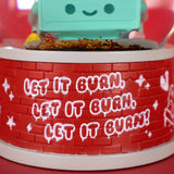 A close-up of 100% Soft’s Dumpster Fire Snow Globe features red with graffiti-style